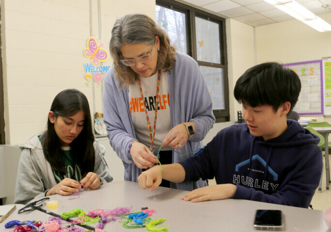 Fort Lee teacher Kimberly Bouchard works with members of the Yarn Crafters Club