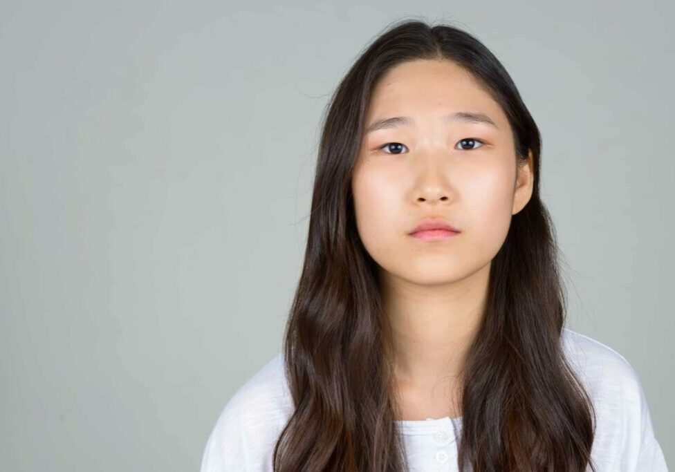 Young beautiful Asian woman wearing white shirt against white background