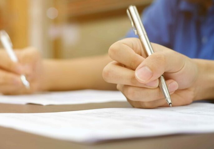 close up group of asian man hand writing answer and solve exam to paper sheet after finish reading question , quiz exercise in class for next examination , university education concept