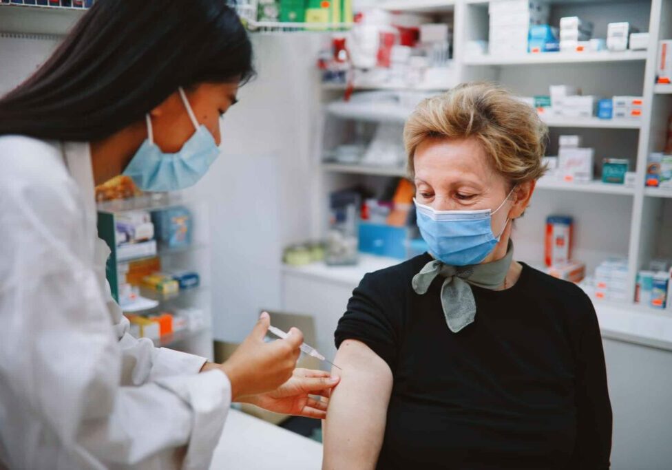Asian nurse giving flu vaccine to a senior patient