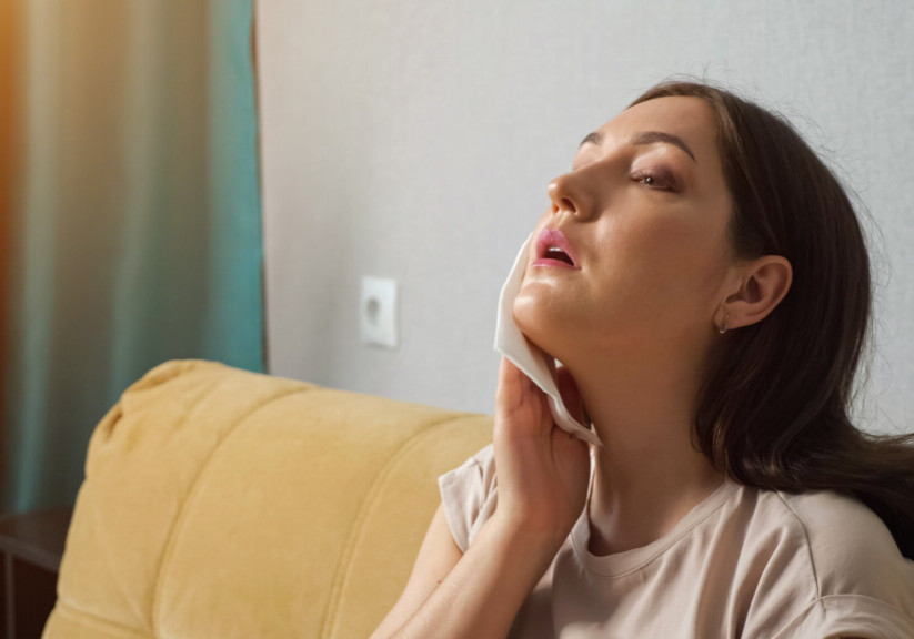Brunette woman suffering from the heat, wiping herself off with a paper napkin