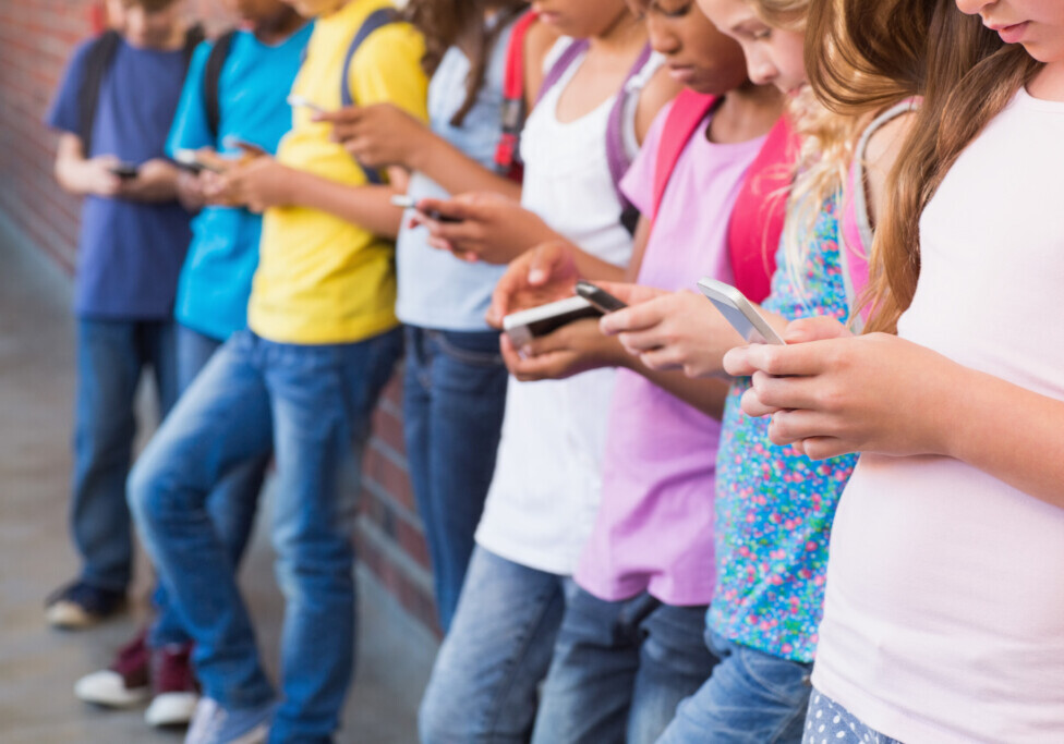 Cute pupils using mobile phone at the elementary school