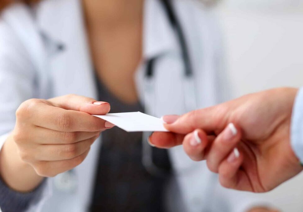 Female physician hand give white blank calling card