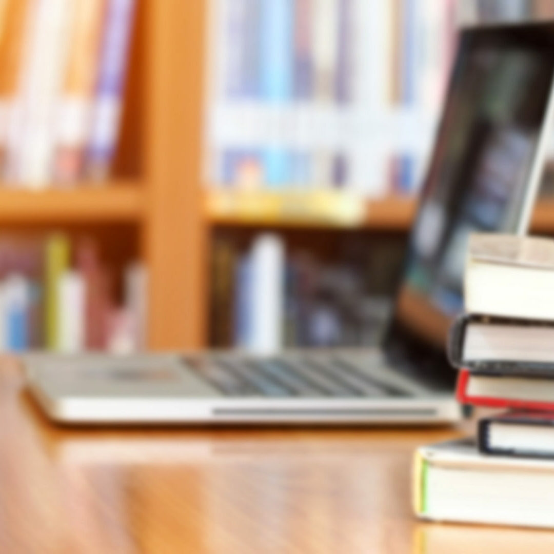 open laptop with books in a pile