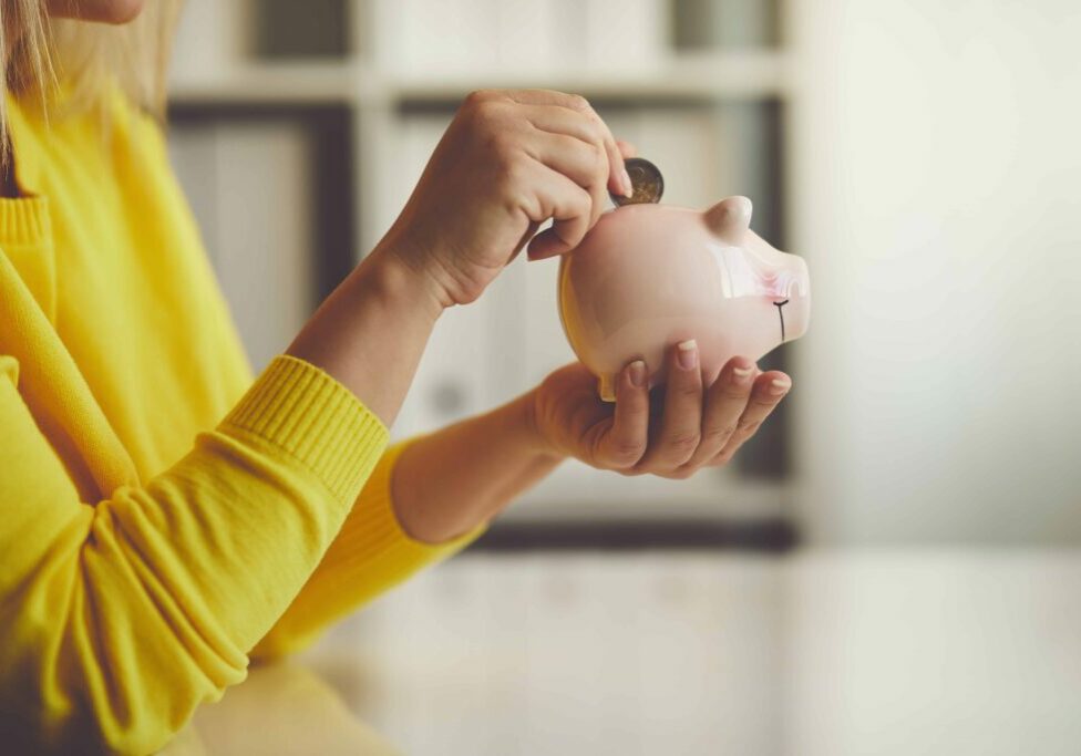 Woman inserts a coin into a piggy bank