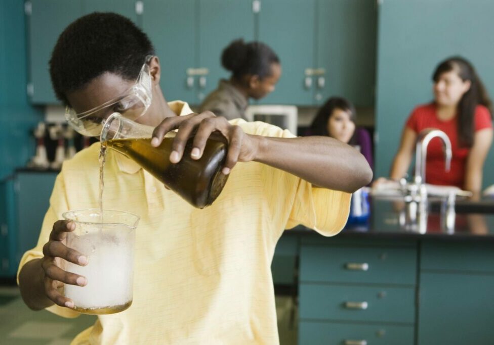 teenage boy performing experiment in chemistry lab