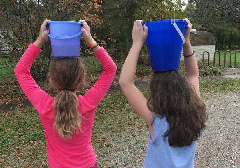 students carry buckets of water